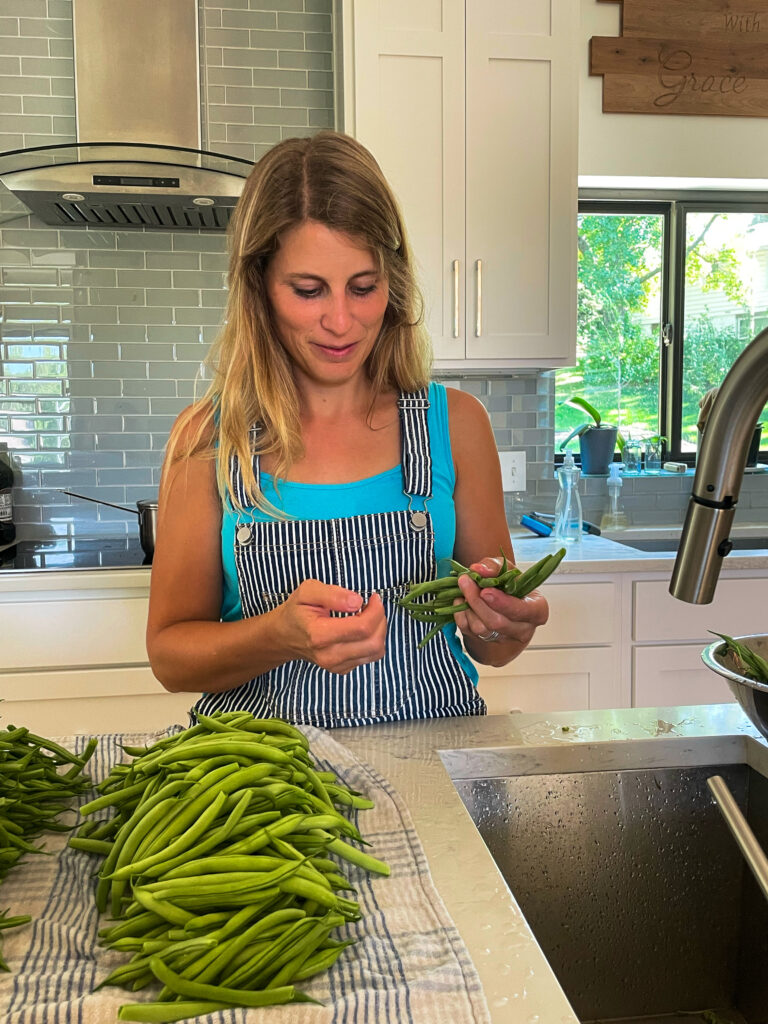 a woman cleaning her fresh picked green beans