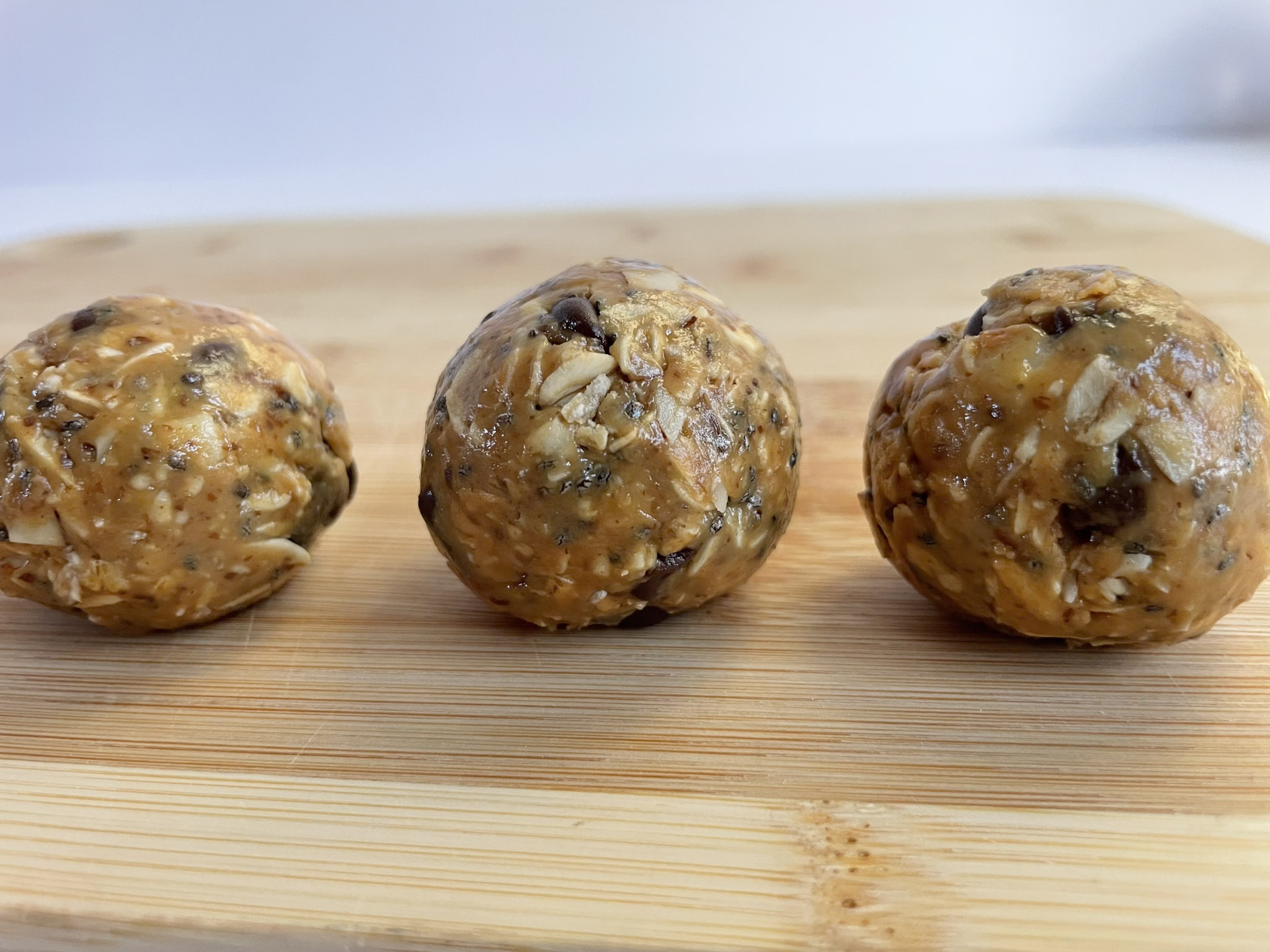 three peanut butter energy bites on a wooded board