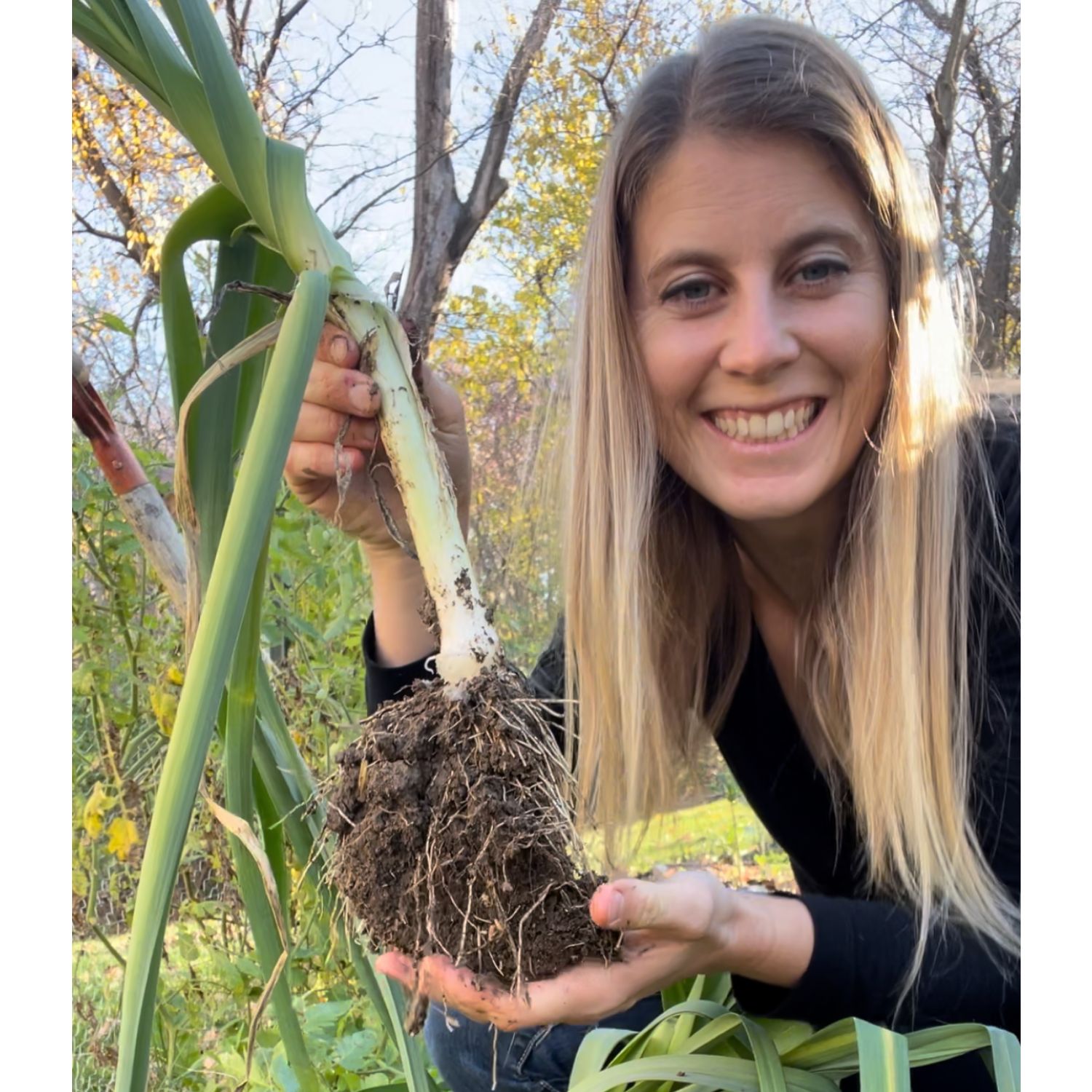 woman holding a leek that was just uprooted.