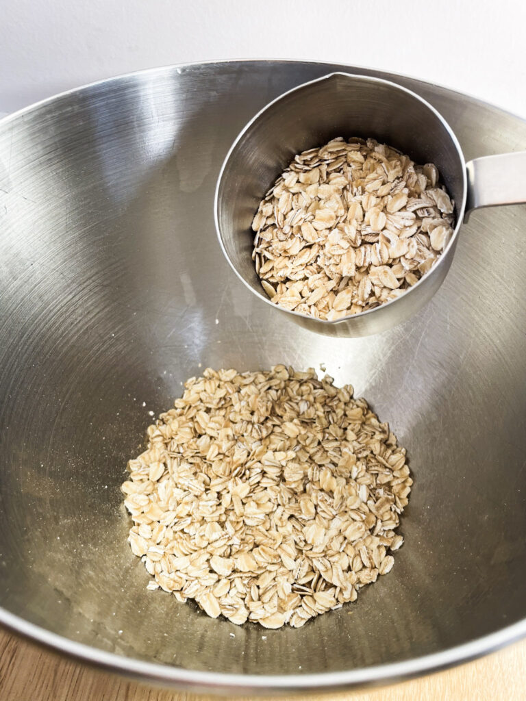 Old-fashion oats in a measuring cup and in a metal mixer bowl