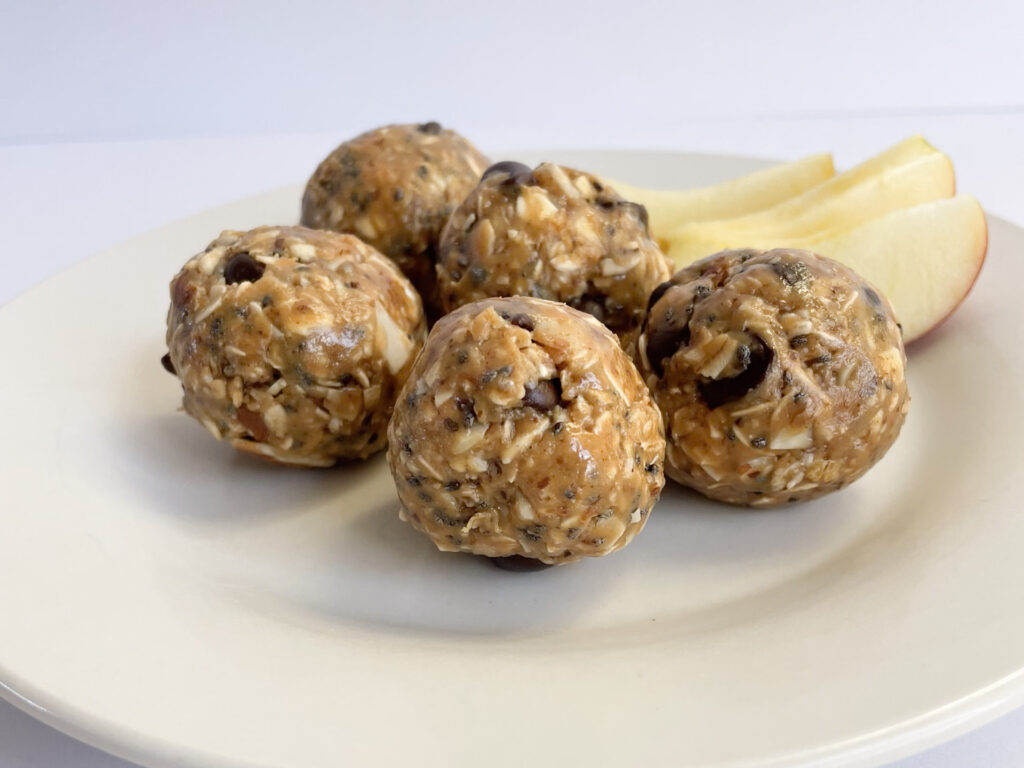 peanut butter energy energy bites with apples slices on a white plate