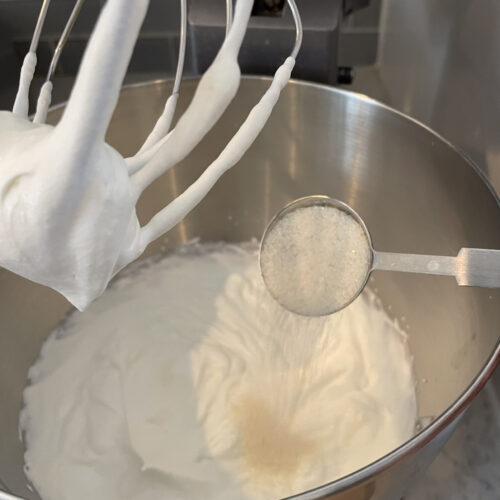 stand mixer whipping heavy cream and a tablespoon of sugar